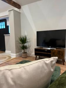 a living room with a large television and a couch at Springfield Lodge - Adorable New Forest 1-bedroom guest house in Ringwood
