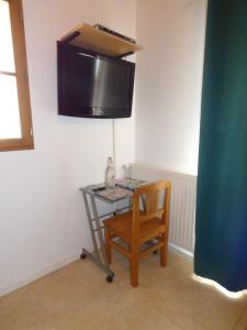Una mesa con una silla y un televisor en una pared. en Escale Vendéenne - Chambre d'hôtes Vendée Globe, en Saint-Révérend