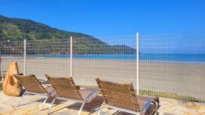 a group of chairs sitting next to a fence at Pousada Areia e Mar in Ubatuba