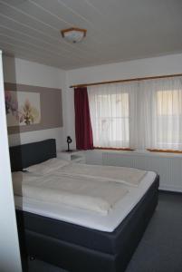 Un dormitorio con una cama grande con sábanas blancas. en Ferienwohnung-Stricker-1-1, en Walkenried