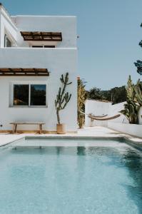 a swimming pool in front of a house with a cactus at Casa Stellar - boutique villa with private heated pool and sea view - sustainably solar powered in Sant Josep de sa Talaia