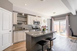 a kitchen with white cabinets and a counter with stools at GLOBALSTAY Waterfront 20Ppl 5 Bedroom Townhouse Hot tub Sauna in Hamilton