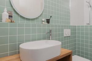 a bathroom with a white sink and green tiles at AuraKarwendel in Scharnitz