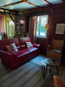 un soggiorno con divano rosso e tavolo di Chalet des pins d'Autriche a Comblain-Fairon