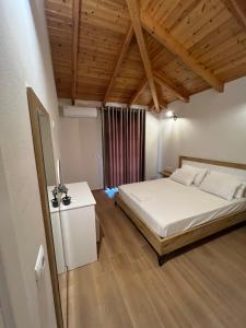 une chambre avec un lit blanc et un plafond en bois dans l'établissement Amazing familiar apartments and rooms, à Saranda