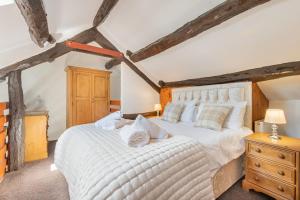 um quarto com uma grande cama branca e tectos em madeira em Cottage 1, Old Farmhouse Mews em Braithwaite