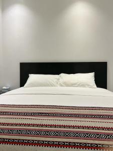 a neatly made bed with a white comforter at Wadi Al Arbeieen Resort in Muscat