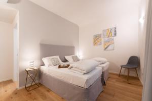 a white bedroom with two beds and a chair at Accademia - Flo Apartments in Florence