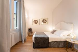 a white bedroom with a bed and a window at Accademia - Flo Apartments in Florence