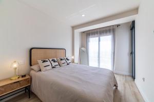 een witte slaapkamer met een groot bed en een raam bij Edificio México in Roquetas de Mar