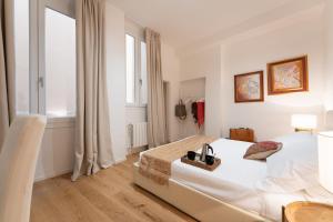 a white bedroom with a bed and a window at Accademia - Flo Apartments in Florence