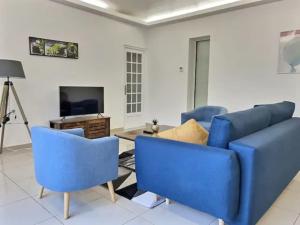 ein Wohnzimmer mit einem blauen Sofa und Stühlen in der Unterkunft CHATENAY 3 in Châtenay-Malabry