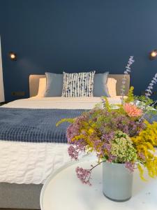 een blauwe slaapkamer met een bed met een tafel met bloemen bij Salt Garden Apartments in Druskininkai