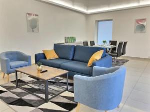 ein Wohnzimmer mit einem blauen Sofa und Stühlen in der Unterkunft CHATENAY 3 in Châtenay-Malabry