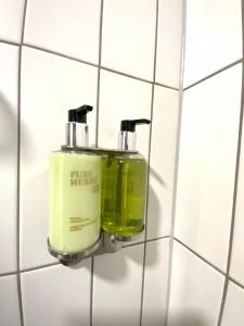 two soap dispensers on a tiled bathroom wall at Salt Garden Apartments in Druskininkai