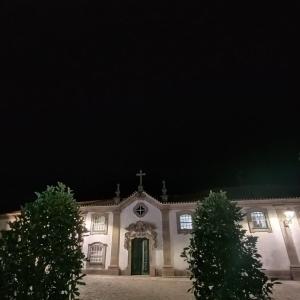 una iglesia con una cruz delante de ella por la noche en Solar dos Carvalhos en Sernancelhe
