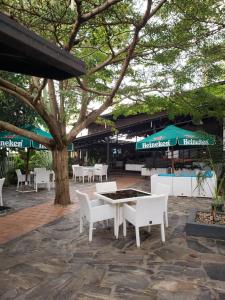 une terrasse avec des chaises blanches, une table et un arbre dans l'établissement La Villa Residence Hotel, à Kigali