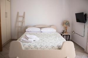 a white bed in a room with a television at Hara's Studio in Perdika