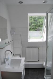 ein weißes Bad mit einem Waschbecken und einem Fenster in der Unterkunft Ferienwohnung Stricker  Typ B, Balkon 2/2 in Walkenried