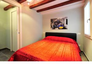a bedroom with a bed with a red comforter at Palace La Vida Apartments in Venice
