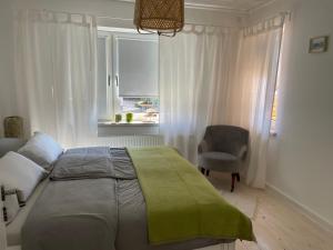 een slaapkamer met een bed, een stoel en een raam bij Relitto Sommerhaus in Borkum