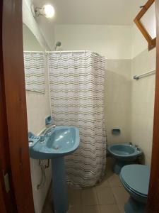 uma casa de banho com um lavatório azul e um WC. em MAKTUB HOSTERIA em El Bolsón