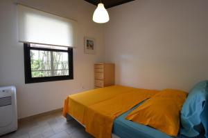 a bedroom with a bed with a yellow comforter and a window at Casa Mykines 