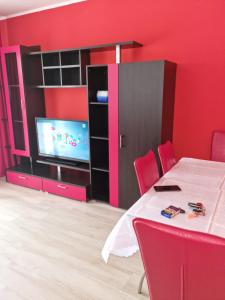 a room with a table and a tv and red walls at Apartament Mia in Ocnele Mari