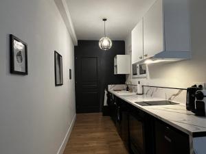 a kitchen with white cabinets and a black door at CK Suite & Spa Reims in Reims
