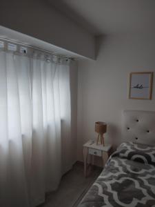 a bedroom with white curtains and a bed and a table at Dpto de 1 dormitorio en el centro de la ciudad in Rosario