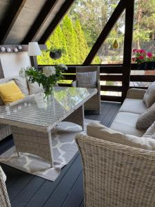 a patio with a glass table and wicker chairs at Apartament Hanuszówka in Nysa