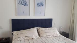 uma cama com uma cabeceira azul e duas almofadas brancas em Green Park em Punta del Este