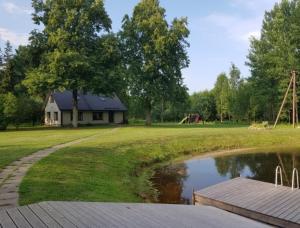 a house in a park with a pond and a playground at Väike-Puusmetsa puhkemaja in Valtina