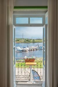 a room with a window with a table and boats in the water at Naval Guest House & Bistrô in Vila do Conde