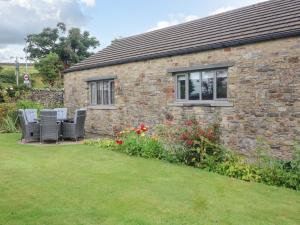 a stone house with chairs and flowers in front of it at Glen Lea in Settle