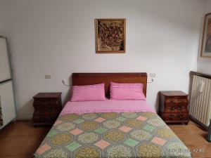 een slaapkamer met een bed met roze lakens en 2 tafels bij CasaVacanze Salza nel Borgo in Sutri