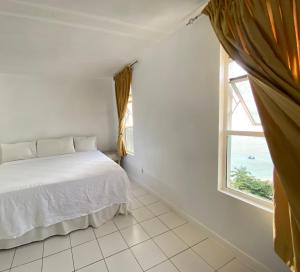 a white bedroom with a bed and a window at Deluxe Montego Bay Club Studio & Suites in Montego Bay