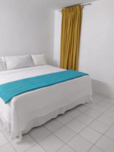 a bedroom with a white bed with a yellow curtain at Deluxe Montego Bay Club Studio & Suites in Montego Bay