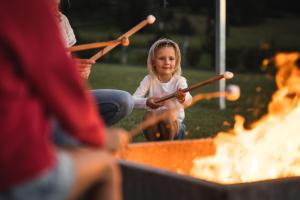 a little girl playing with paddles around a fire at Family Aparthotel Winklwiese in Valdaora