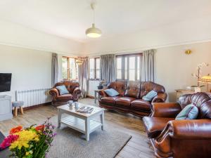 a living room with leather furniture and a table at Tyn Morfa in Pwllheli