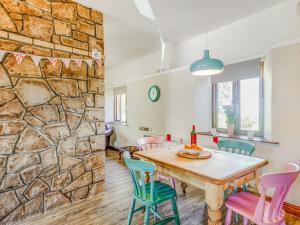 una sala da pranzo con parete in pietra e tavolo e sedie in legno di Tyn Morfa a Pwllheli