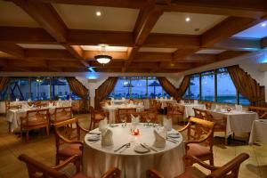 un restaurante con mesas y sillas blancas y ventanas en Atana Khasab Hotel, en Khasab