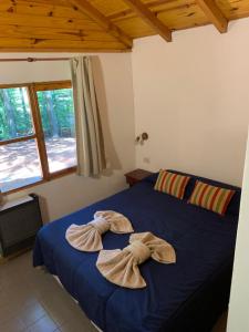 Un dormitorio con una cama azul con toallas. en CABAÑAS AILIN-CO, en El Bolsón