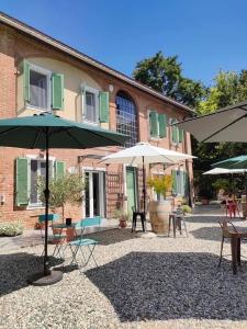 eine Terrasse mit Tischen und Sonnenschirmen vor einem Gebäude in der Unterkunft Noi Due - Bed & Breakfast nel Monferrato in Quargnento