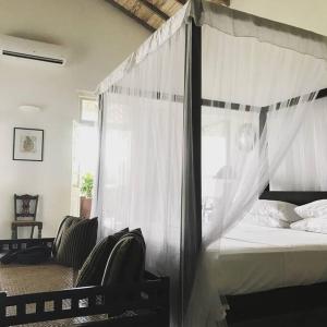 a bedroom with a canopy bed with white curtains at ETAMBA HOUSE in Galle