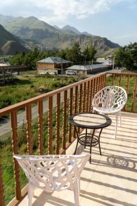 2 sillas y una mesa en una terraza con montañas en Hotel Diamond Kazbegi, en Kazbegi