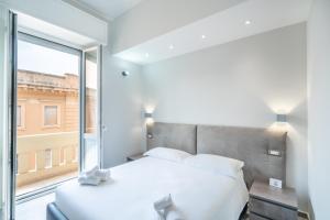 um quarto com uma cama branca e uma grande janela em Kuzu apts - City Center - WiFi AC TV em Cagliari