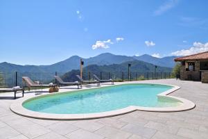 uma piscina com cadeiras e montanhas ao fundo em COCO em Venaco