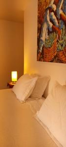 ein Bett mit Kissen und ein Gemälde an der Wand in der Unterkunft Casa da Ilha Inn, Ilha Grande in Abraão