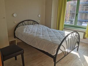 1 cama en un dormitorio con silla y ventana en APPARTEMENT WESTENDE (DRIEMASTER), en Middelkerke